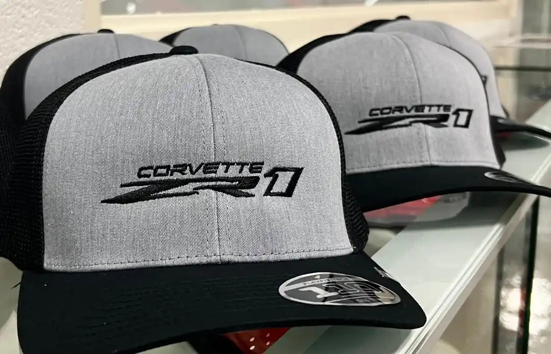 Gray and black trucker-style baseball caps with Corvette logos embroidered on the front.